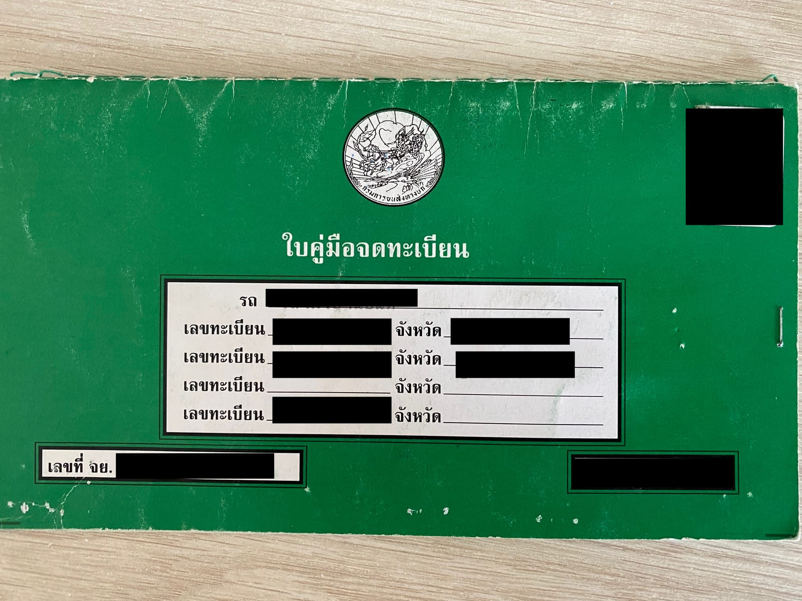 The green cover of a Thai vehicle registration book, closed